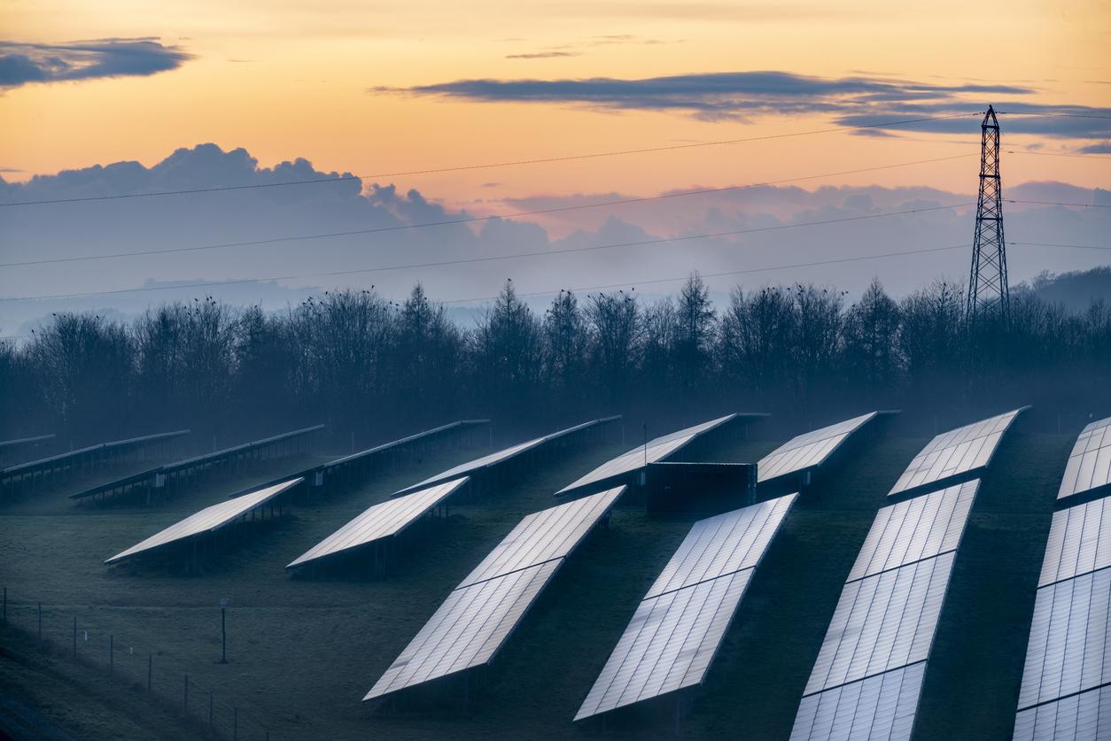 An image of solar panels in a field at sunset